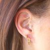 Close-up of an ear wearing gold hoop earrings with a blurred background