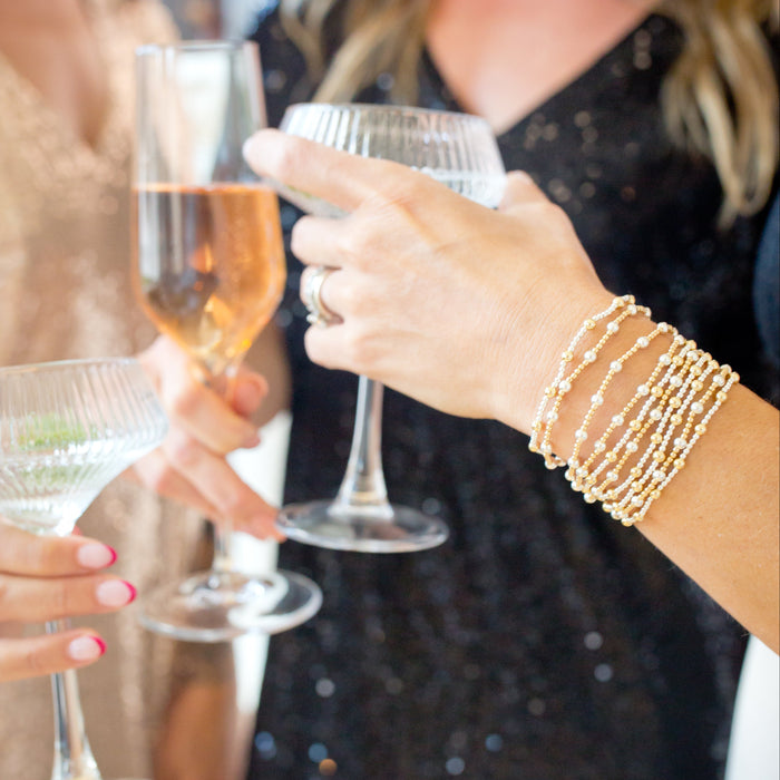 Two women clinking glasses of champagne at a social event.