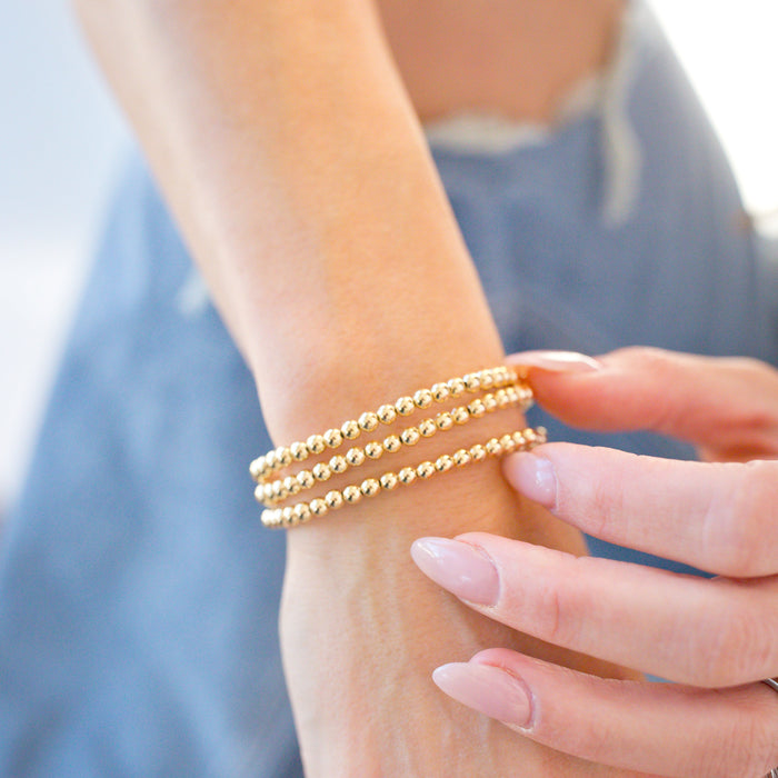 Close-up of a hand wearing gold bracelets with a blurred background