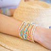 Close-up of a person's arm wearing colorful beaded bracelets on a blurred background