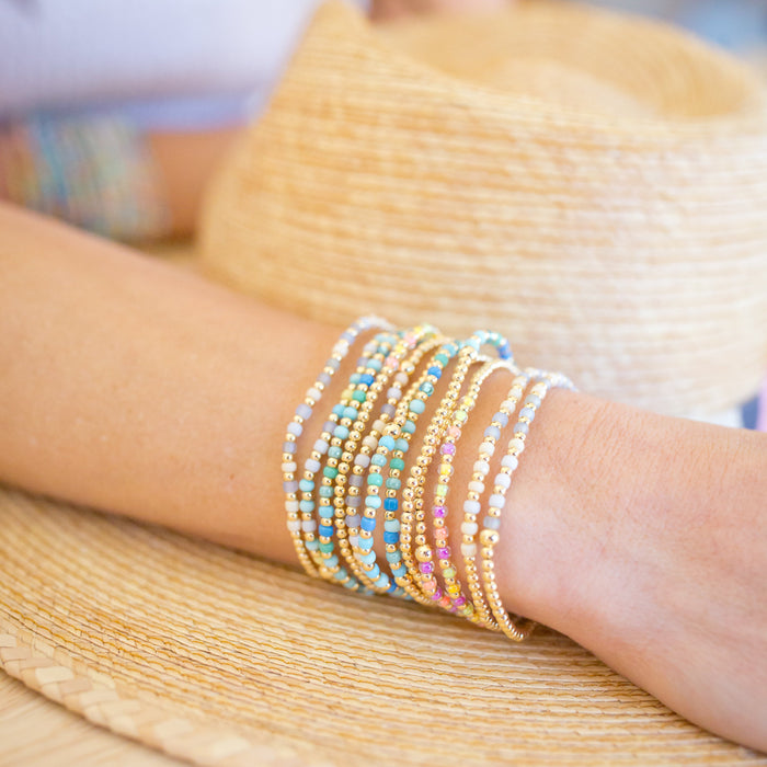Close-up of a person's arm wearing colorful beaded bracelets on a blurred background