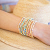 Close-up of a person's arm wearing colorful beaded bracelets on a blurred background