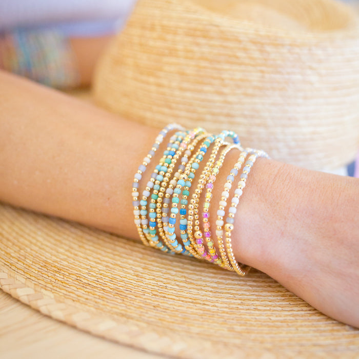 Close-up of a person's arm wearing colorful beaded bracelets on a blurred background