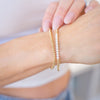 Close-up of a person's wrist wearing two pearl bracelets on a blurred background