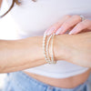 Close-up of a person wearing two pearl bracelets on a blurred background
