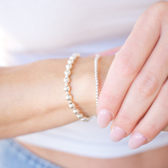 Close-up of a hand wearing a pearl bracelet with a blurred background