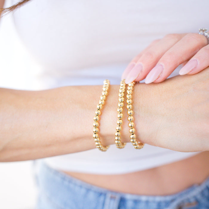 Gold bracelets on a wrist with a blurred background