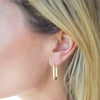 Close-up of a person wearing a gold hoop earring.