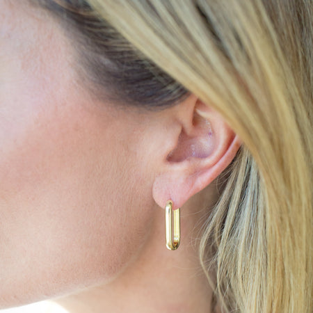 Close-up of a person wearing a gold hoop earring.