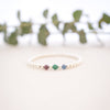 Gold bracelet with colored beads on a white surface with blurred green leaves in the background