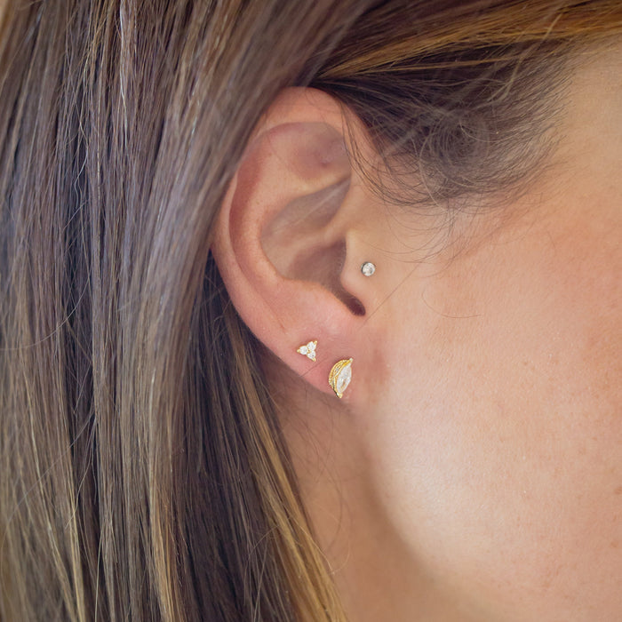 Close-up of an ear wearing gold earrings with a blurred background