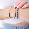 Close-up of a person's wrist wearing two beaded bracelets on a blurred background