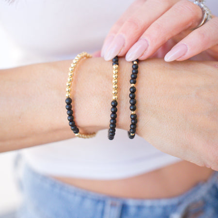 Close-up of a person's wrist wearing two beaded bracelets on a blurred background