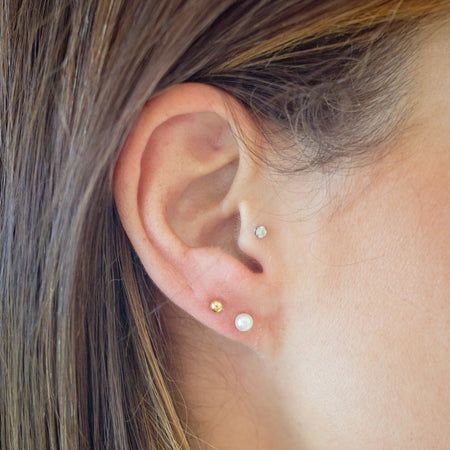 Close-up of an ear with pearl earrings against a blurred background