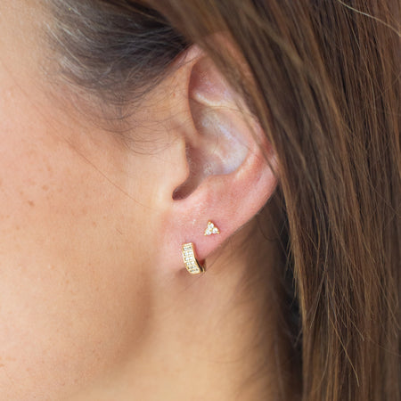 Close-up of an ear wearing gold earrings with a blurred background