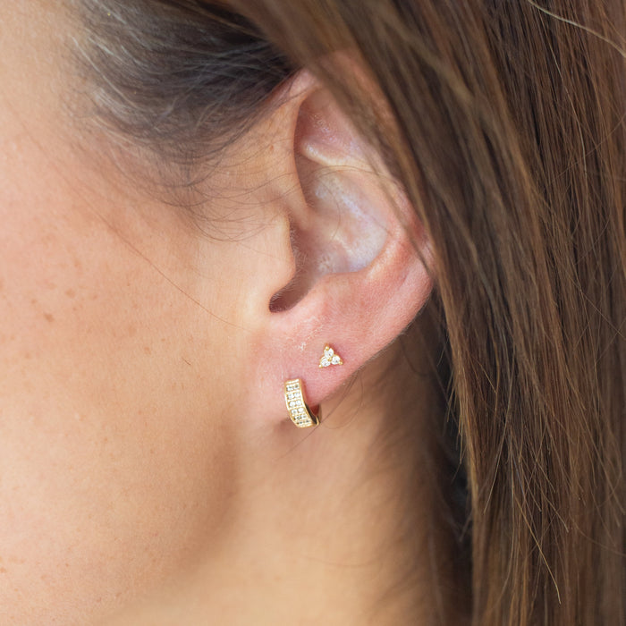 Close-up of an ear wearing gold earrings with a blurred background