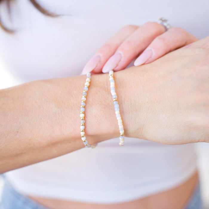 Close-up of a person wearing two beaded bracelets on a blurred background