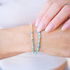 Close-up of a hand wearing a beaded bracelet on a plain background