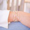 Close-up of a wrist wearing multiple pearl bracelets on a blurred background