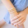 Gold beaded bracelet with freshwater pearl three bracelets stacked up on wrist 