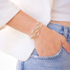 Person wearing a gold bracelet on a white background