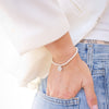 Person wearing a pearl bracelet with a blurred background