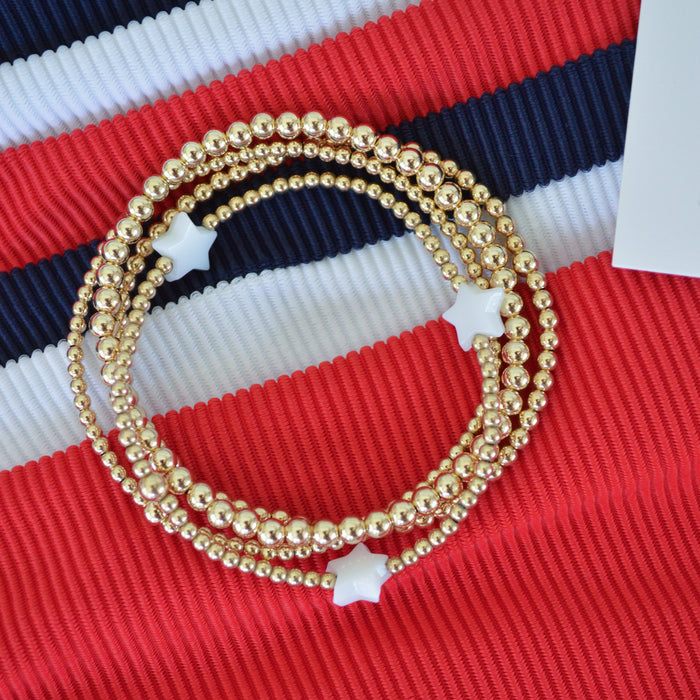 Gold beaded bracelet on a red, white, and blue striped background