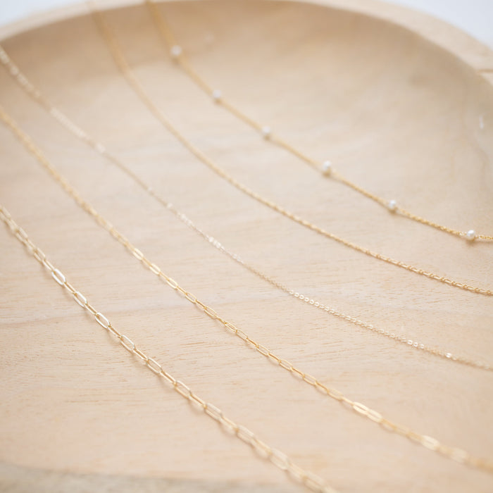 Gold chain necklace on a marble surface with a light background