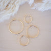 Set of gold hoop earrings on a soft beige background