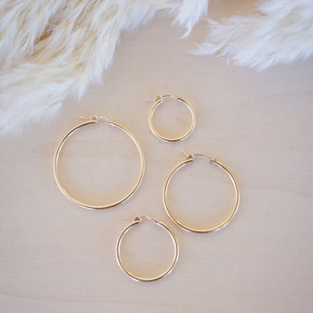 Set of gold hoop earrings on a soft beige background