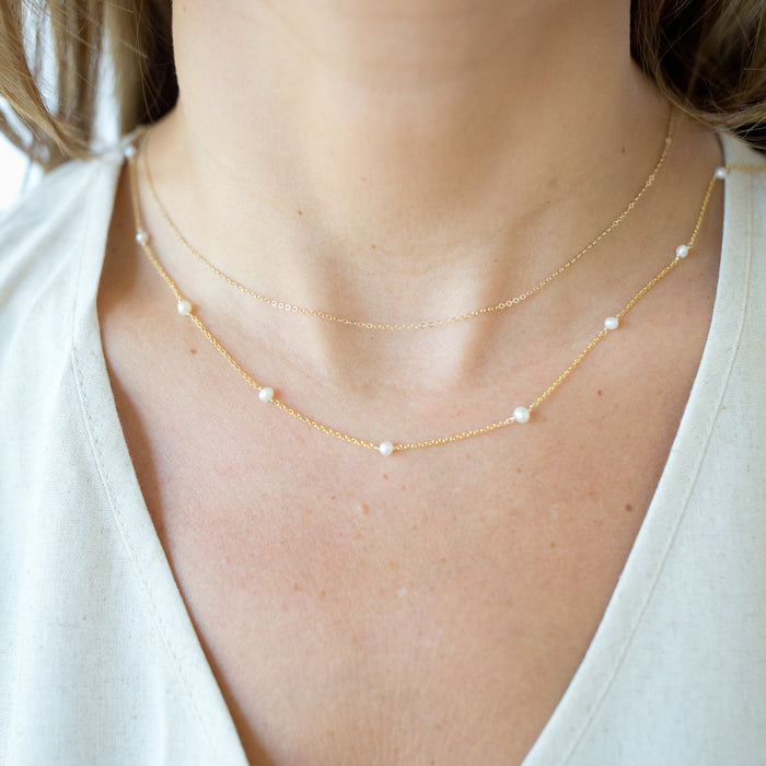 Necklace with small beads on a person wearing a white top