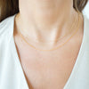 Gold necklace on a person wearing a white top