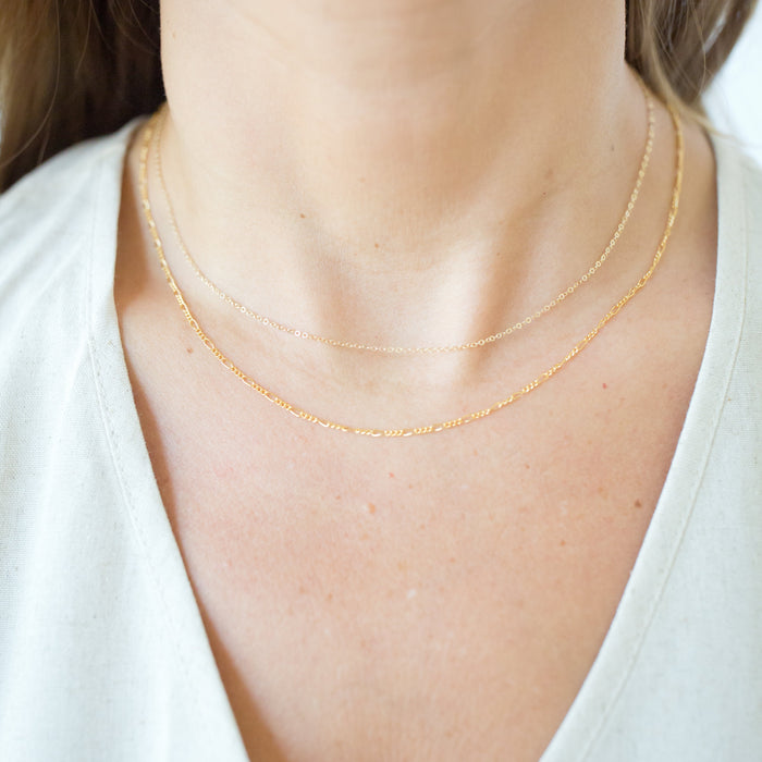 Gold necklace on a person wearing a white top