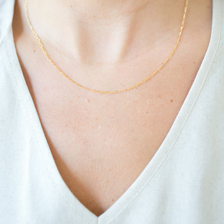 Gold necklace on a person wearing a white shirt