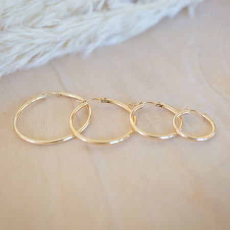 Set of gold hoop earrings on a soft fabric background