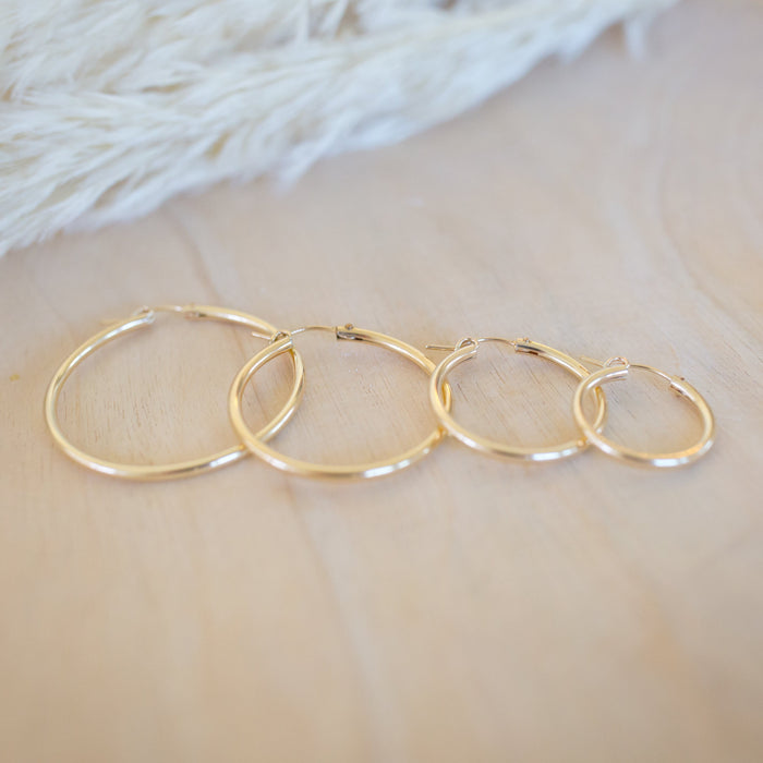 Set of gold hoop earrings on a soft fabric background