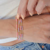 Close-up of a person wearing colorful beaded bracelets on a white background