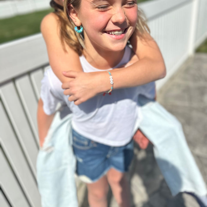Two young girls playing outdoors, one giving a piggyback ride.