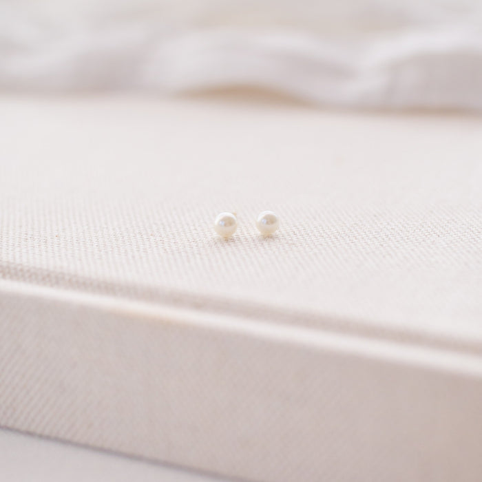 Pearl earrings on a soft white fabric background