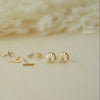 Collection of gold earrings on a neutral background