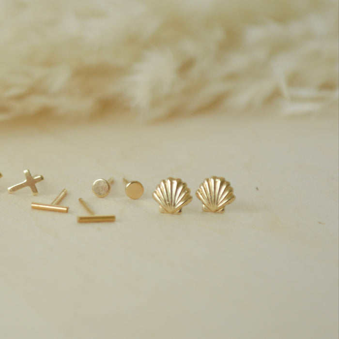 Collection of gold earrings on a neutral background