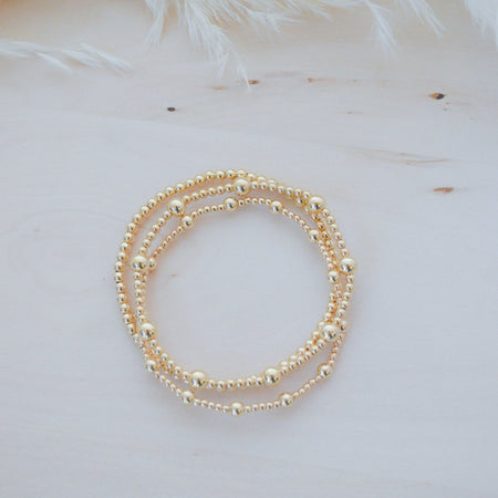Gold beaded bracelet on a light background