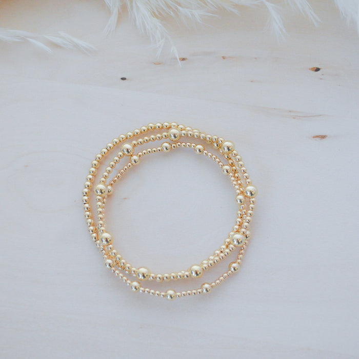 Gold beaded bracelet on a light background