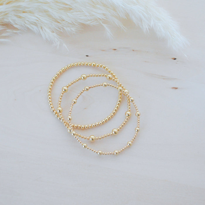 Gold beaded bracelet on a soft white background