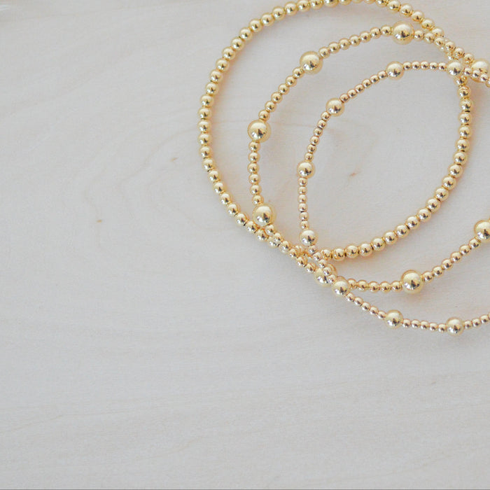 Gold bracelet on a white feather background