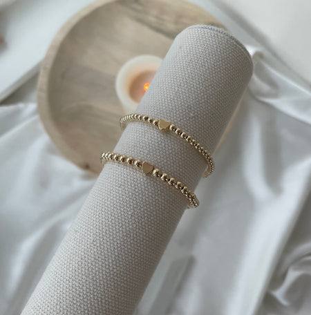 Gold bracelets on a white surface with a soft focus background