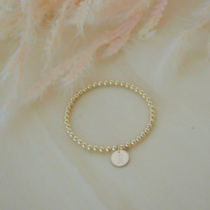 Pearl bracelet with a gold tag on a soft, light-colored background