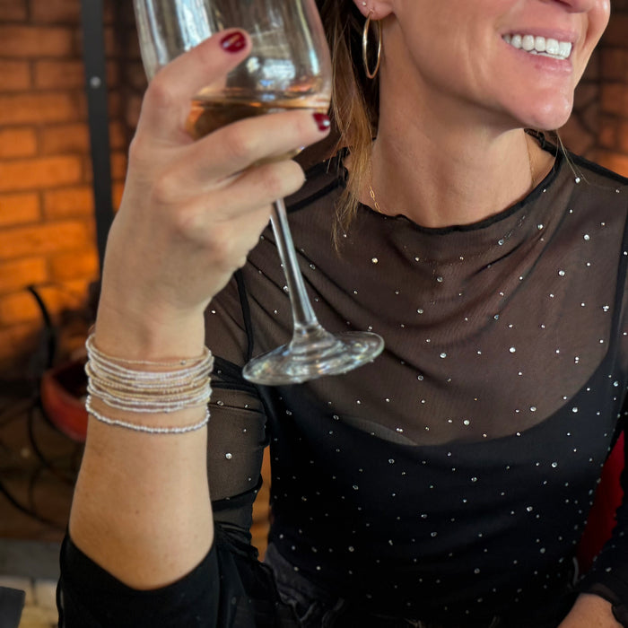 Woman in a black dress with star patterns holding a glass of wine indoors.