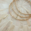A gold-filled corrugated beaded bracelet with amethyst and opal beads, displayed on a white textured background.