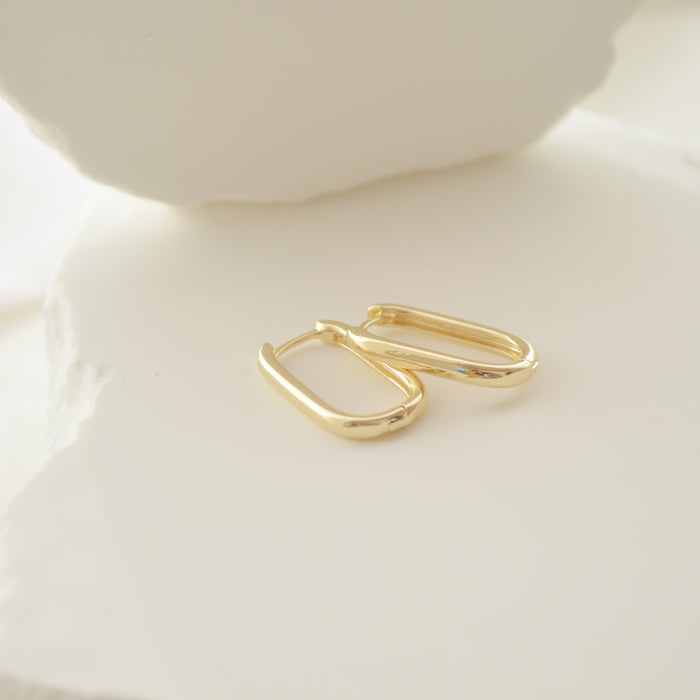 Gold hoop earrings on a light beige surface